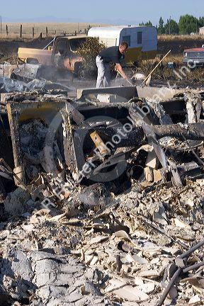 Victim sifts through the rubble of a home destroyed by wildfire near Mountain Home, Idaho.