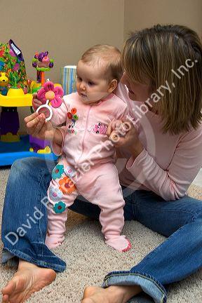Mother and infant child playing with a toy rattle. MR