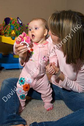 A mother with her infant child playing with a toy rattle. MR