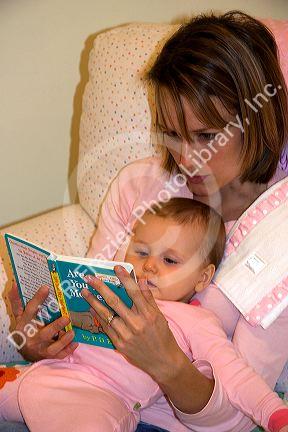 A mother reading a book to her infant child. MR