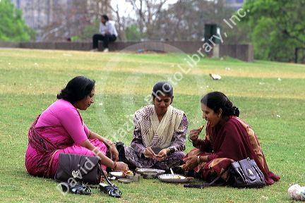 Indian women eating lunch on the grass in India.