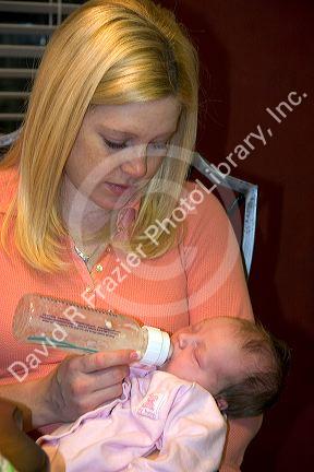 A new mother feeding her baby daughter with a bottle. MR