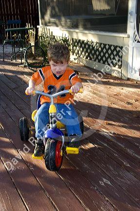A three year old boy riding a tricycle in Florida. MR
