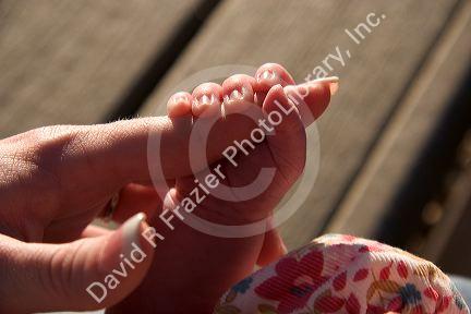 Baby girl holding her mother's finger.