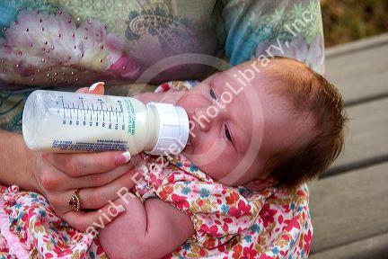 Mother bottle feeding her newborn baby daughter. MR