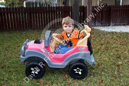 Three year old boy riding in a battery powered toy car. MR