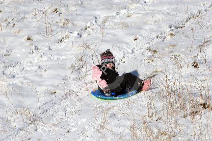 A young girl sledding down a snow covered hill in Idaho. MR