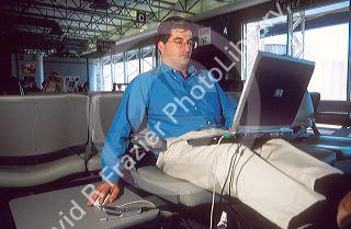 Man using a laptop computer at airport waiting area.