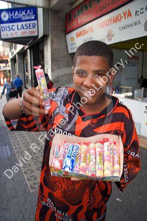A boy selling candy on the street in the Liberdade asian section of Sao Paulo, Brazil.