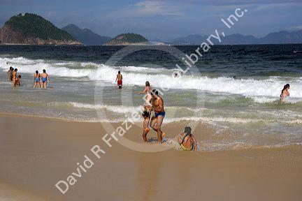 Visitors play in the waves at Copacabana Beach in Rio de Janeiro, Brazil.