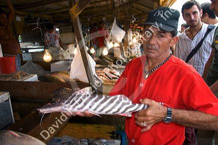 Vendor selling catfish at a market in Manaus, Brazil.