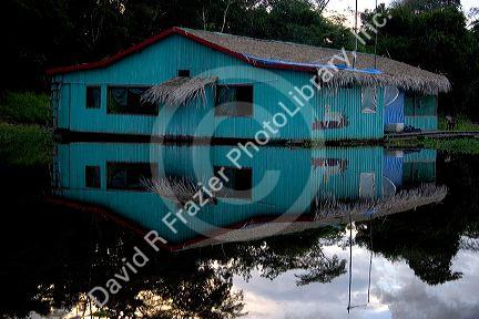 A rustic hotel  reflected in the water on the Arasa River in the Amazon jungle near Manaus, Brazil.