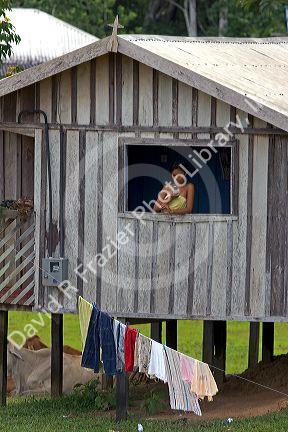 Brazilian girl seen in the window of her house using a cell phone in the Amazon jungle near Manaus, Brazil.