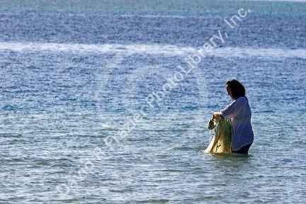 Tahitian woman net fishing off the island of Moorea.