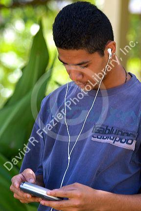Teenage boy listening with head phones to a cd player on the island of Moorea.