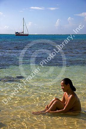 Tahitian woman sitting topless in the lagoon off the island of Moorea. MR