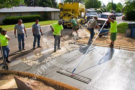 Workers pouring and leveling a concrete driveway in Boise, Idaho.