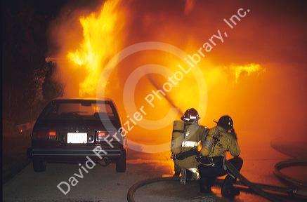 Firemen fighting a house fire with water.