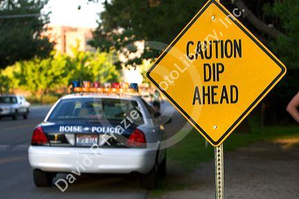 Road sign warning of dip ahead and a police car in Boise, Idaho.