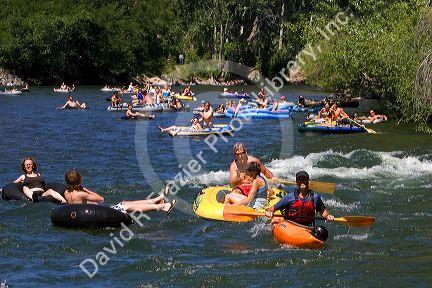 People on inflatable rafts and a kayak floating the Boise River in Boise, Idaho.