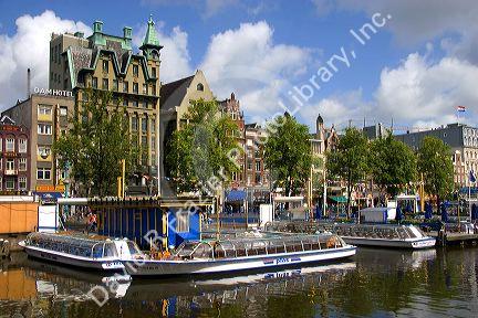 Tour canal boats on the Damrak canal in Amsterdam, Netherlands.