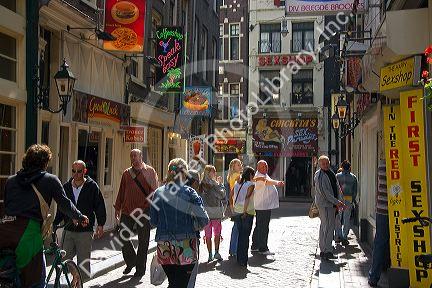 People and store fronts on a walking street in the Red Light District of Amsterdam, Netherlands.