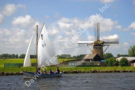 Sailing past a windmill on a canal east of Leiden in the province of South Holland, Netherlands.