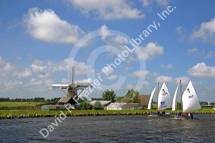 Sailing past a windmill on a canal east of Leiden in the province of South Holland, Netherlands.