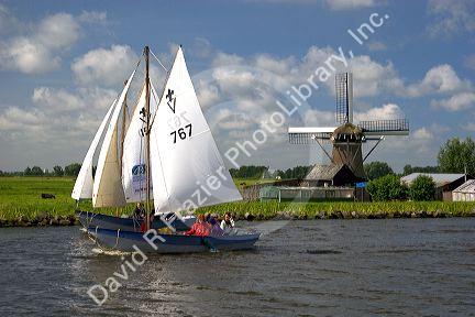 Sailing past a windmill on a canal east of Leiden in the province of South Holland, Netherlands.