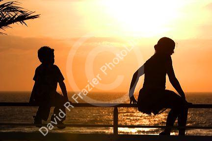 Silhouette of children at sunset by the sea.
