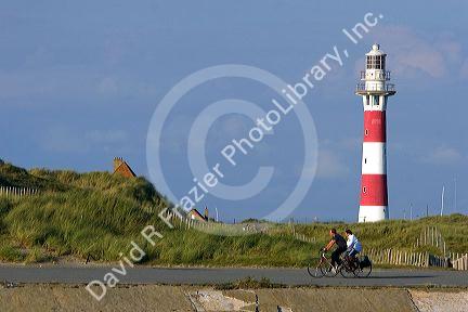 People ride bicycles past the Nieuwpoort Lighthouse at Nieuwpoort in the province of West Flanders, Belgium.