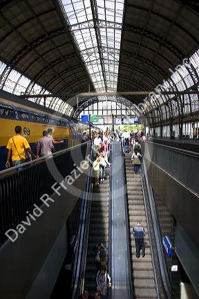 Passengers ride on escalators and await trains at Amsterdam Central Station, Stationsplein, Amsterdam, Netherlands.