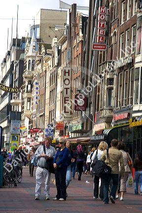 People walk the Damrak Strasse in Amsterdam, Netherlands.