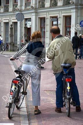 Tourists on bicycles read a map on the street in Amsterdam, Netherlands.
