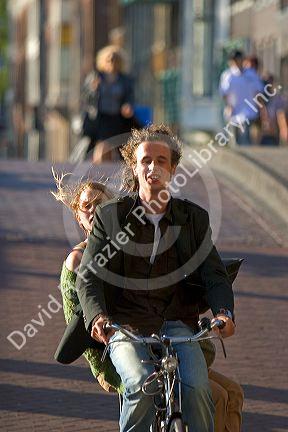 Man and woman ride a bicycle on the street in Amsterdam, Netherlands.