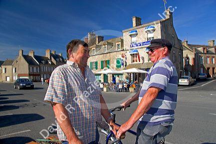 French men talk on the street in the village of Barfleur in the region of Basse-Normandie, France.
