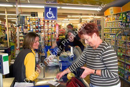 French woman pays for her groceries at a super market in the village of Barfleur in the region of Basse-Normandie, France.