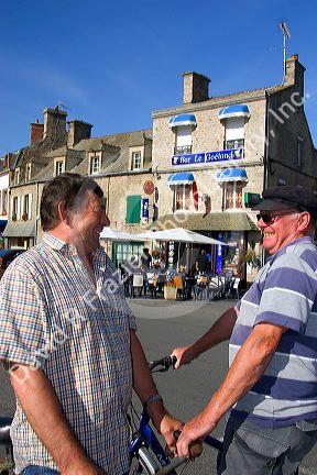 French men talk on the street in the village of Barfleur in the region of Basse-Normandie, France.