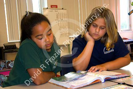 Fourth grade students read a textbook in a classroom at a public school in Tampa, Florida.