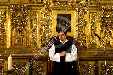A priest performing mass in front of a gold alter inside the Catedral Metropolitana located on the central square, the zocalo, Mexico.