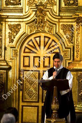 A priest performing mass in front of a gold alter inside the Catedral Metropolitana located on the central square, the zocalo, Mexico.