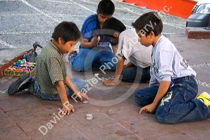 Mexican boys play a game of pogs in the plaza at Taxco in the State of Guerrero, Mexico.