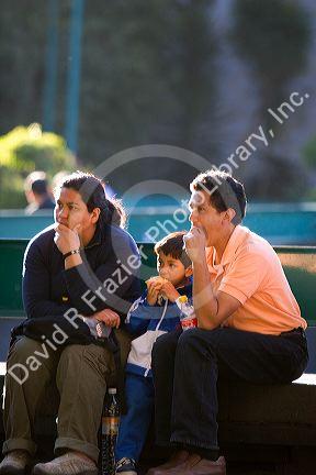 Mexican family sits on a bench in Chapultepec Park, Mexico City, Mexico.