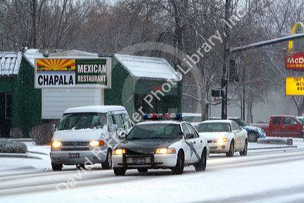 Police car and traffic drive on snowy roads in Boise, Idaho.