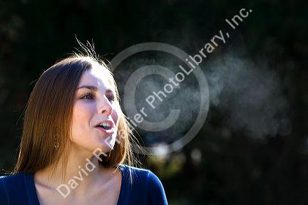 Young woman exhaling into cold outdoor air. MR