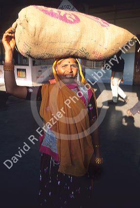Indian woman carrying a bag on her head in India.