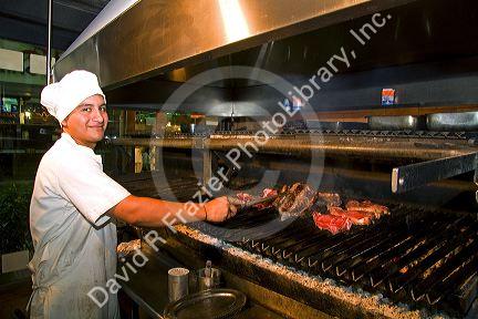 Argentine man grilling meat at a restaurant in Buenos Aires, Argentina.