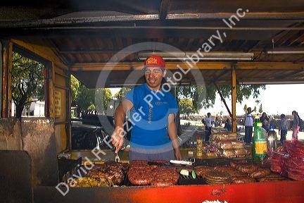 Street vendor grilling meat along the Rio de la Plata in Buenos Aires, Argentina.