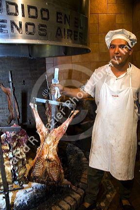 Argentine man cooking meat in a pit at a restaurant in Buenos Aires, Argentina.