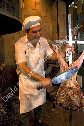Argentine man cooking meat at a restaurant in Buenos Aires, Argentina.